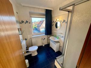 ein Badezimmer mit Toilette und Waschbecken und einem Fenster in der Unterkunft Haus Elbe Wohnung #15 - 10 min zu Fuß zum Strand in Cuxhaven + 10 Fotos