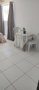 um piso em azulejo branco com uma mesa e 2 cadeiras em Hostel da Prainha em Marechal Deodoro