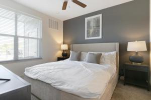 a bedroom with a bed with white sheets and two lamps at Landing Modern Apartment with Amazing Amenities ID8348X93 in Kansas City