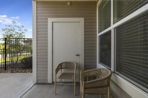 two chairs sitting on a porch with a door at Landing Modern Apartment with Amazing Amenities ID8348X93 in Kansas City