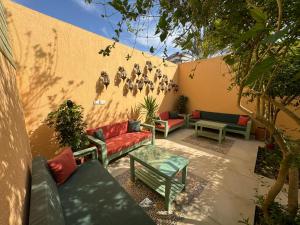 un patio con sofás, una mesa y una pared en Beit Reihana, en Dahab