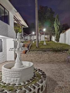 une fontaine blanche devant un bâtiment la nuit dans l'établissement Casa La Riviera, à Santa Rosa de Cabal
