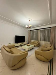 a large living room with couches and a tv at Hello sunshine in Dar es Salaam