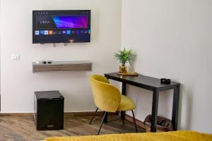 a desk with a yellow chair and a television on a wall at Lustru Apartment in Catania +29 photos