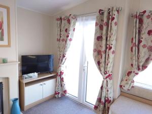 um quarto com uma janela com cortinas e uma televisão em Idyllic mobile home in beautiful surroundings em Porchfield