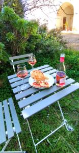 Salento Houses & Idro Suites في ناردو: طاولة نزهة مع طبق من الطعام وكأسين من النبيذ