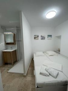 a white room with two beds and a sink at Logement T2 au coeur du village in Gruissan