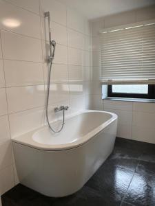 Luxe Appartement Marc في آرنم: حوض استحمام أبيض في حمام مع نافذة