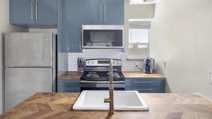 La cuisine est équipée de placards bleus et d'un four avec plaques de cuisson. dans l'établissement Landing - Modern Apartment with Amazing Amenities (ID3736X50), à Denver