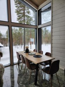 a dining room with a table and chairs and windows at Levin Huvilompolo in Kittilä