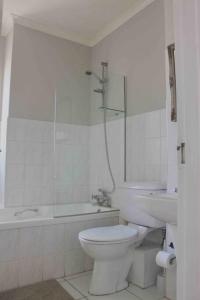 a white bathroom with a toilet and a bath tub at Dolphins 25 Stay in Gqeberha +27 photos