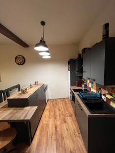 a kitchen with black cabinets and a wooden floor at L'industriel , T2 hyper centre cosy in Montauban