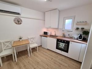 een keuken met witte kasten, een tafel en een wastafel bij Kedves Apartman in Pécs