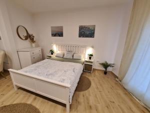 Habitación blanca con cama y espejo en Kedves Apartman, en Pécs