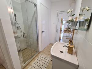 een witte badkamer met een douche en een wastafel bij Kedves Apartman in Pécs