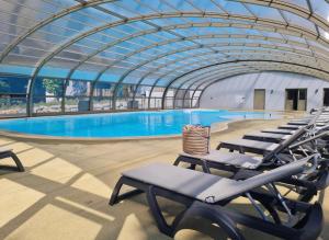 a large swimming pool with lounge chairs in a building at Le Chalet d'Angel in Jullouville-les-Pins +11 photos