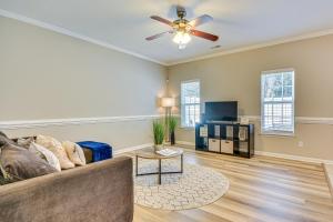 a living room with a couch and a ceiling fan at Charming Greensboro Townhouse with Back Patio! in Greensboro