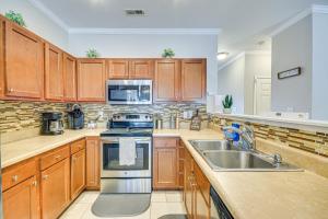 a kitchen with wooden cabinets and a stainless steel sink at Charming Greensboro Townhouse with Back Patio! in Greensboro