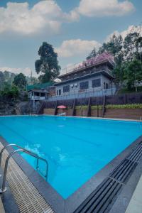 a large blue swimming pool in front of a building at Konfudha Resort in Kalpetta