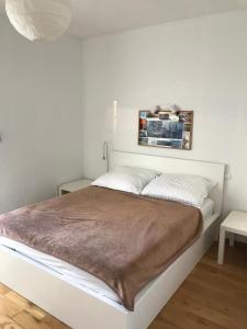 a white bed with a brown blanket on top of it at Apartament nad Czarną Hańczą in Suwałki