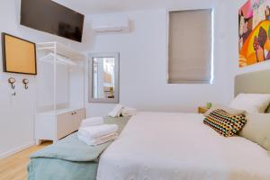 um quarto branco com uma cama grande e uma televisão em Luminosa Holidays House em Olhão