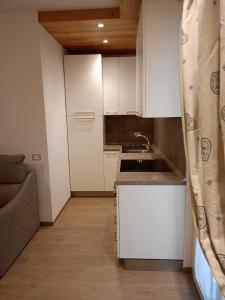 a small kitchen with white cabinets and a sink at CHALET GIOVANNI in Aprica