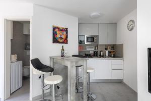 a kitchen with white cabinets and bar stools at Dubrovnik Domus Apartment in Dubrovnik
