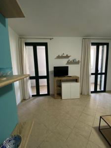 uma sala de estar com portas de vidro deslizantes e uma televisão em Aurora em Santa Cesarea Terme