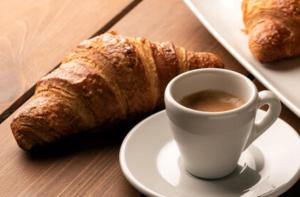 ein Teller mit einer Tasse Kaffee und Croissants auf einem Tisch in der Unterkunft B&B Ristel in Lizzano
