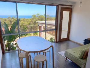 a living room with a table and chairs and a balcony at 4 Bedroom Mid-Century Home with Ocean Views in Bundeena