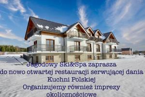 una casa nella neve con le parole "osteopatia pattini psizaza" di Jagodowy Ski & Spa a Lasowka