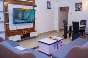 sala de estar con TV de pantalla plana y sillas en Cosystay Apartment, en Abuja