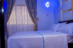 1 dormitorio con 1 cama blanca y ventana en Cosystay Apartment, en Abuja