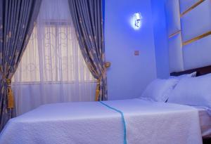 1 dormitorio con cama blanca y ventana en Cosystay Apartment, en Abuja