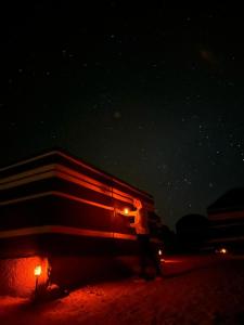 a person standing next to a large building at night at Bedouin host camp& with tour in Wadi Rum