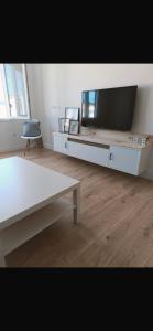 sala de estar con TV, mesa y silla en Precioso piso en Ribeira, en Ribeira