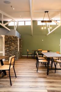a dining room with tables and chairs and a stone wall at Haka House Franz Josef in Franz Josef