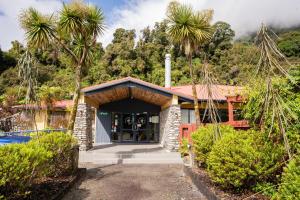 a home with palm trees in the background at Haka House Franz Josef in Franz Josef