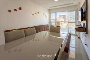 MuquiçabaにあるLindo apto a apenas 400m da Praia do Morro CVE402のテーブルと大きな窓のあるリビングルーム