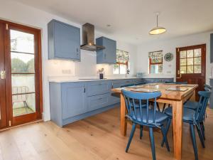 a kitchen with blue cabinets and a wooden table and chairs at Tresawle in Newquay
