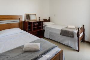 MuquiçabaにあるLindo apto a apenas 400m da Praia do Morro CVE402のベッドルーム1室(ベッド2台、ドレッサー、鏡付)
