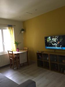 een woonkamer met een tafel en een tv aan de muur bij Maison Jaune in Stains
