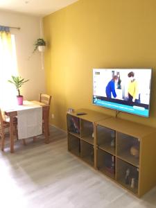 een woonkamer met een flatscreen-tv op een standaard bij Maison Jaune in Stains