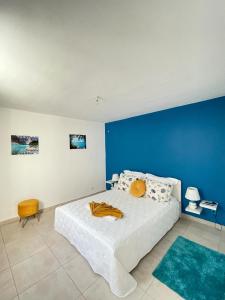 a bedroom with a white bed with a blue wall at Résidence Subtropicale in Saint-François