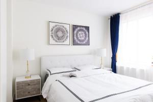 um quarto com uma cama branca e duas fotografias na parede em 75-3C Brand New Duplex 3BR W D in the unit em Nova York