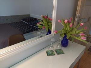 a mirror with two vases of flowers on a table at Pokoje AGA in Mikołajki