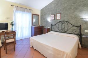 a bedroom with a bed and a desk and a television at Antico Casale Di Scansano Resort in Scansano