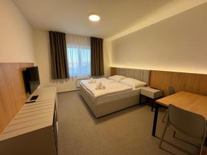 Habitación de hotel con cama y escritorio en Comfort Pálava, Penzion & Restaurant en Klentnice