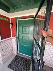 a person opening a door to a green door at Hole in the Wall Getaway USA/Mexico in Columbus