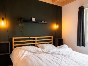 um quarto com uma cama branca e uma parede verde em Cozy chalet with palet stove em De Veenhoop